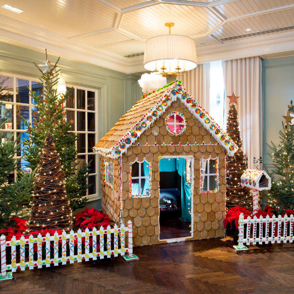 a gingerbread house in a room with trees and lights