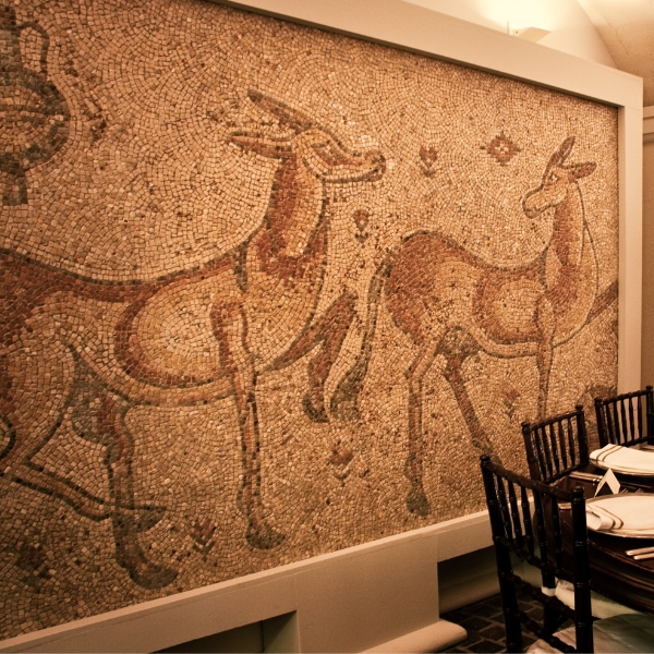 a mosaic wall with a picture of deer and a table with a dining table