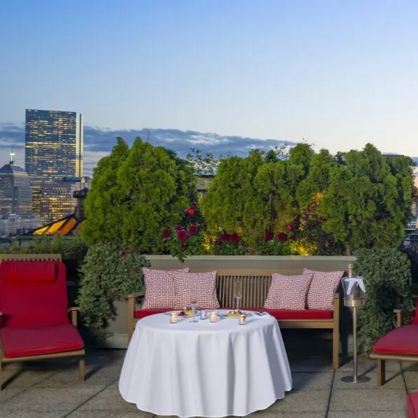 a table with a white tablecloth and red chairs on a rooftop