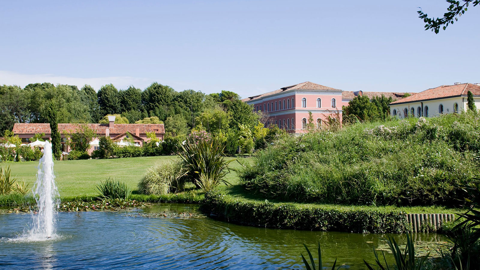 a pond with a pink building and trees 10