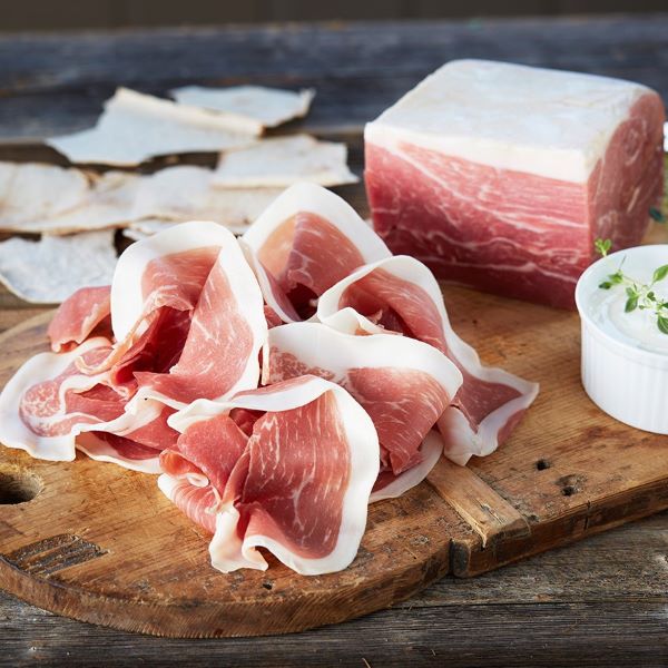 a cutting board with meat and a bowl of sauce