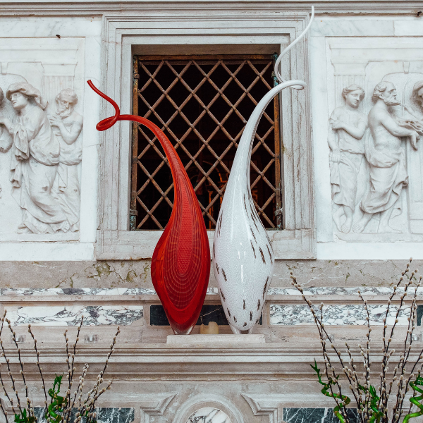 a red and white sculpture on a stone wall