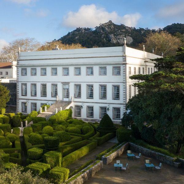a white building with a garden and bushes