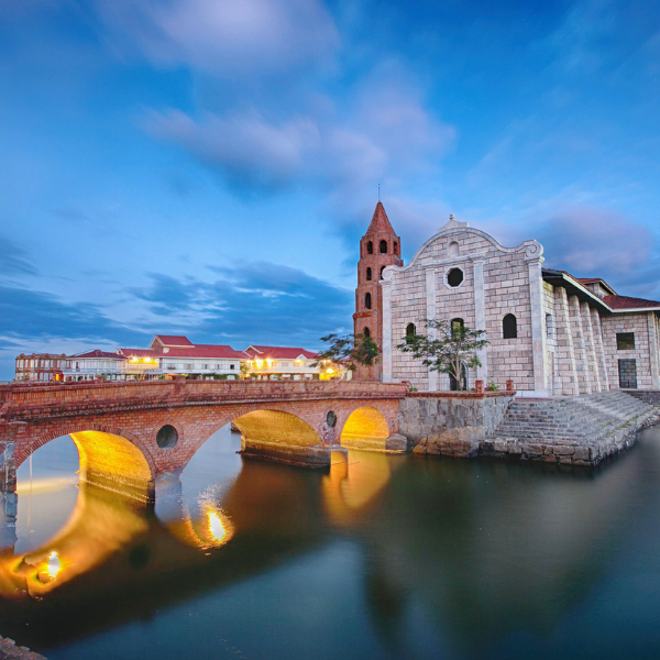 a bridge over water with a building and a tower