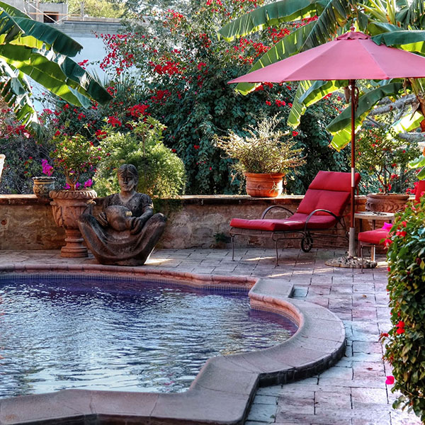 a pool with a pink umbrella and a statue in the middle