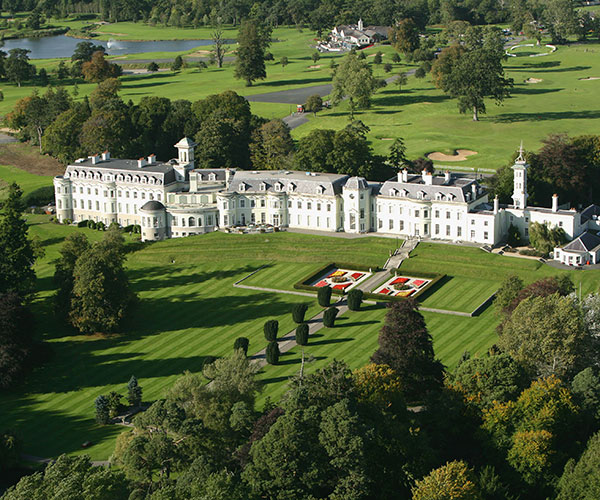 a large white building with a lawn and trees