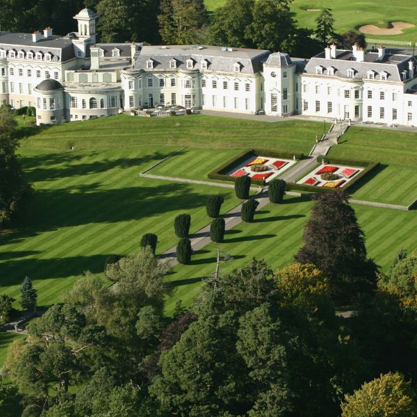a large white building with a lawn and trees