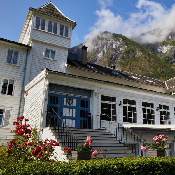 a white building with a blue door and stairs leading to a mountain