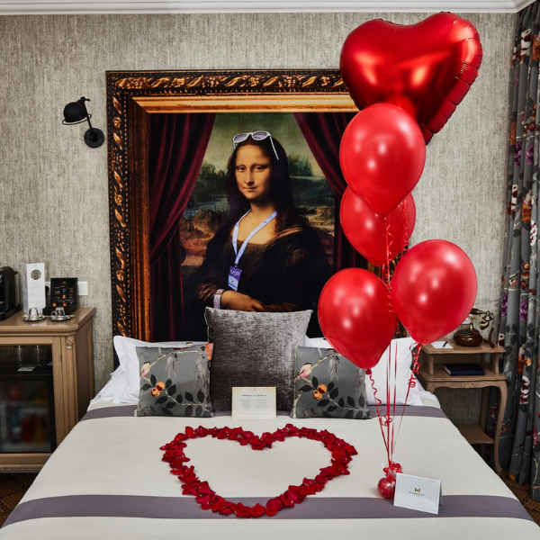 a bed with red balloons and a heart shaped object