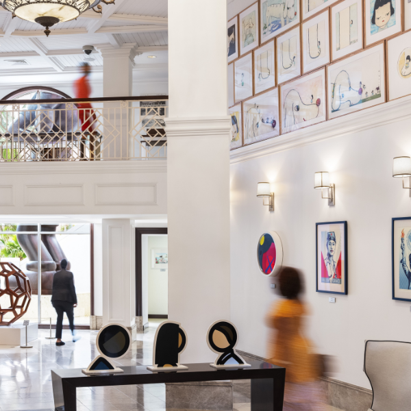 a room with a large white column and a large table with artwork on the wall