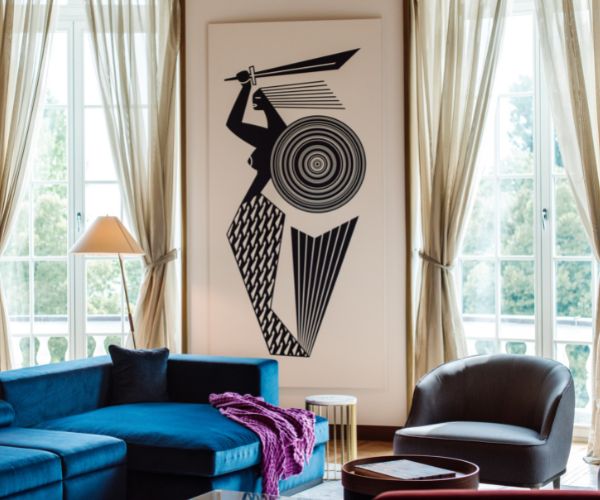 a living room with a blue couch and a picture of a woman holding a sword