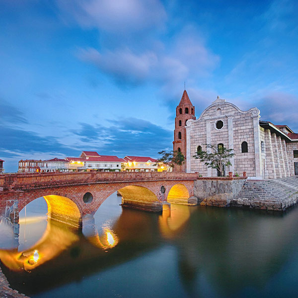 a bridge over water with a building and a tower