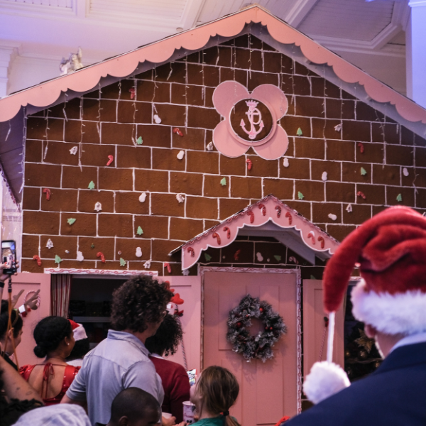 a group of people in a room with a gingerbread house