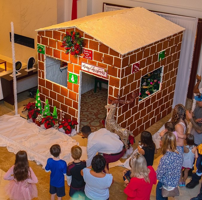 a group of people around a gingerbread house