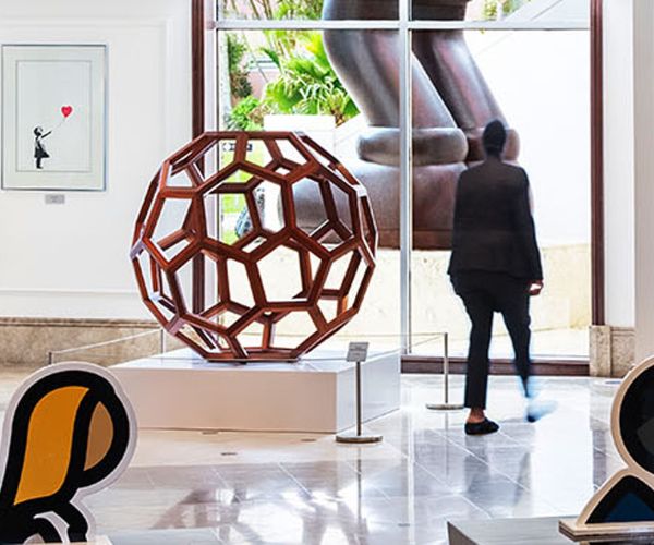 a man walking in a room with a sculpture