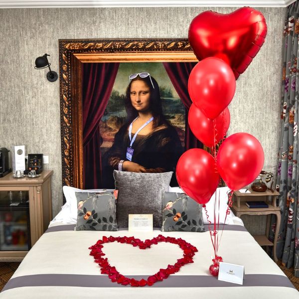 a bed with red balloons and a heart shaped picture