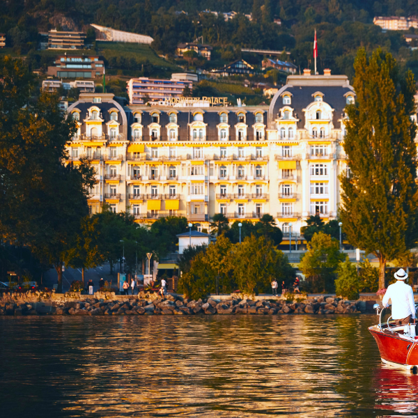 a man in a boat on water with a large building in the background