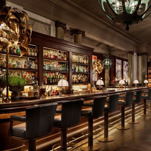 a bar with a row of chairs and a chandelier