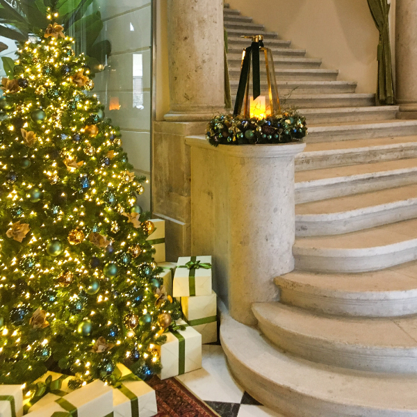 a christmas tree with presents in front of a staircase