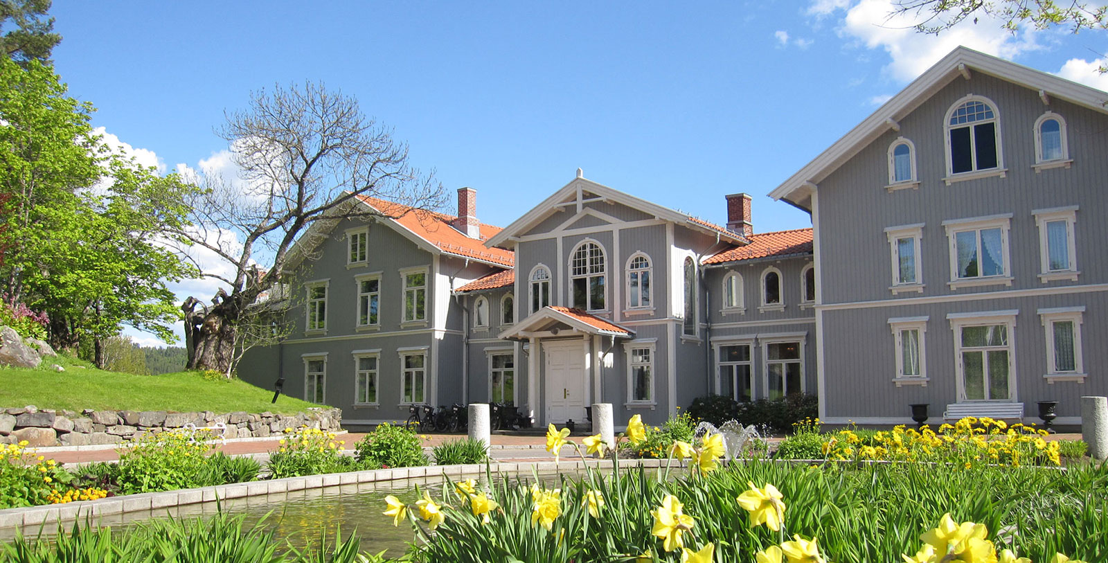 a large house with a pond and flowers 13