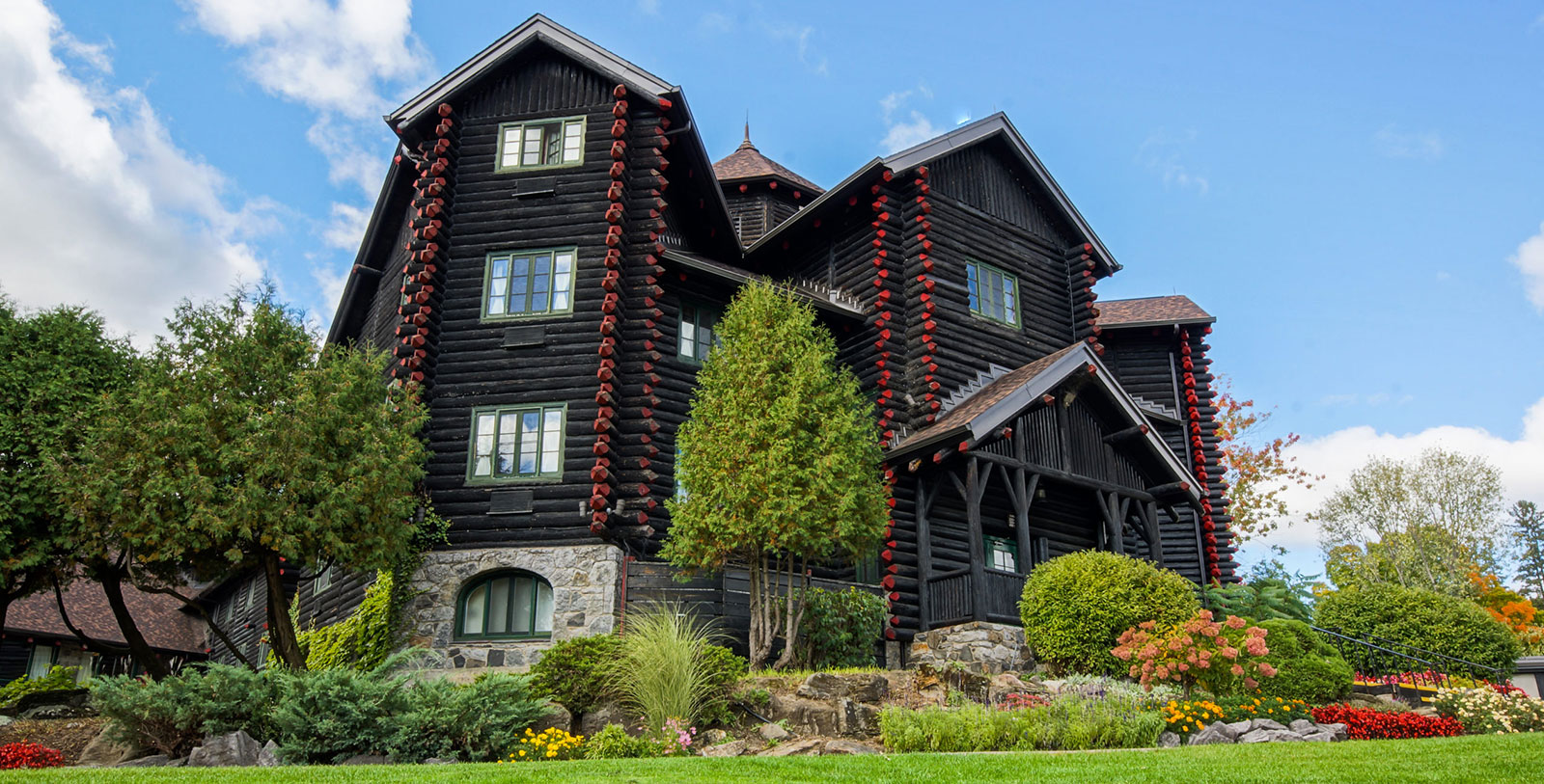 a large log house with trees and bushes