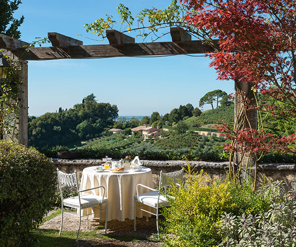 a table and chairs outside with a view of a hill and trees