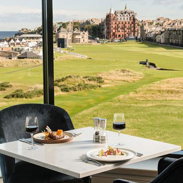 a table with food and wine glasses on it with a golf course in the background