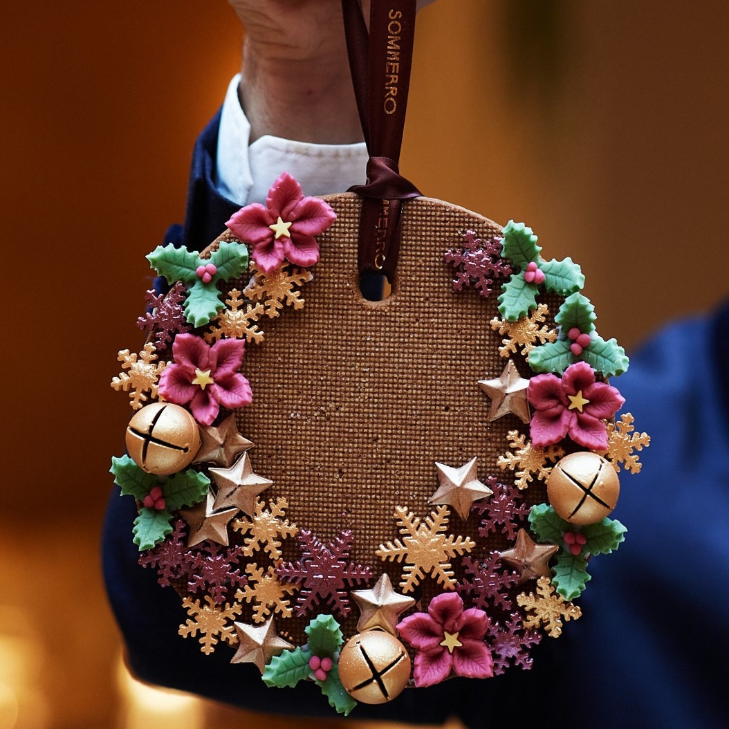 a hand holding a round object with flowers and bells