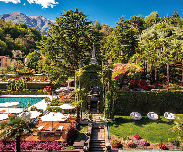 a pool in a garden with chairs and tables