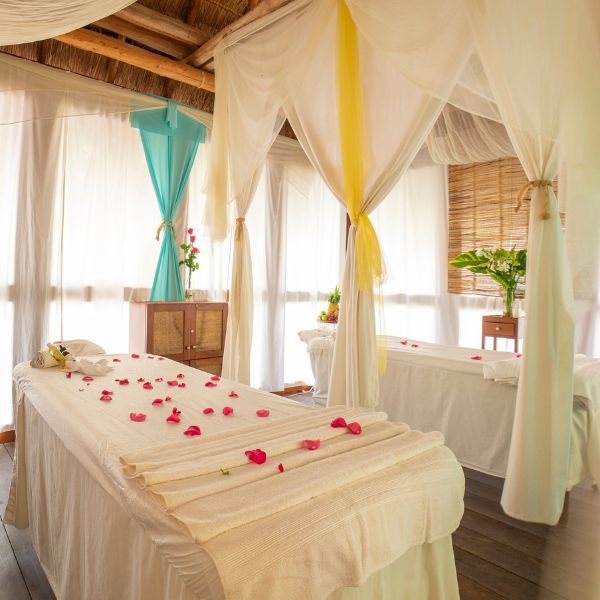 a massage table with white sheets and flowers on it