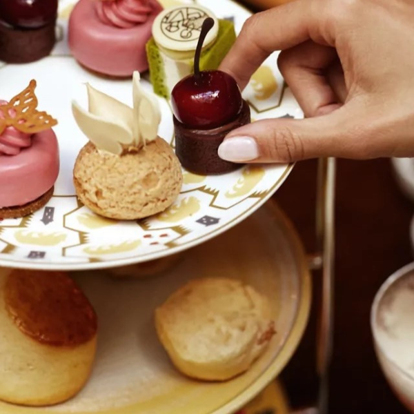 a hand reaching for a plate of desserts