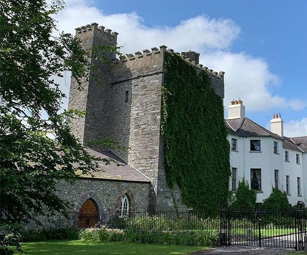 a stone castle with a fence and trees