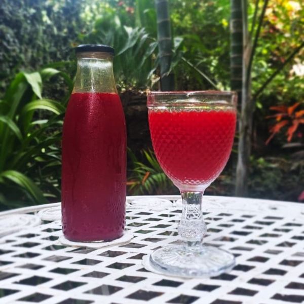 a bottle and glass of red liquid on a white table