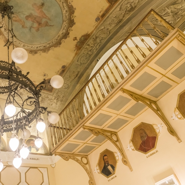 a chandelier with a balcony and paintings on the wall