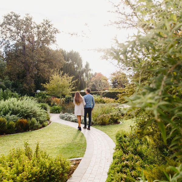 a man and woman walking on a path in a garden