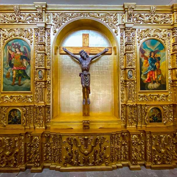a gold wall with a cross and paintings on it