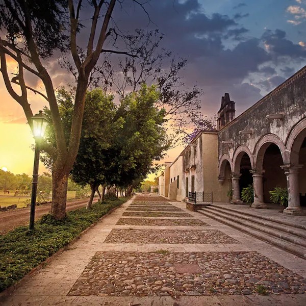 a stone walkway with arches and trees