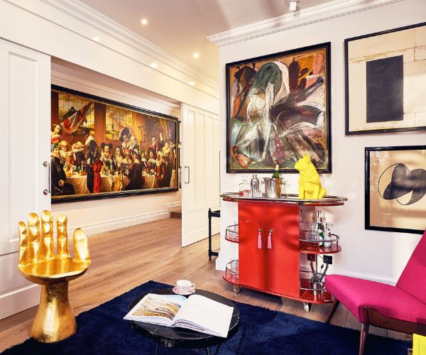 a room with a red cabinet and a gold table and artwork on the wall