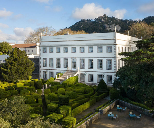a white building with a garden and bushes