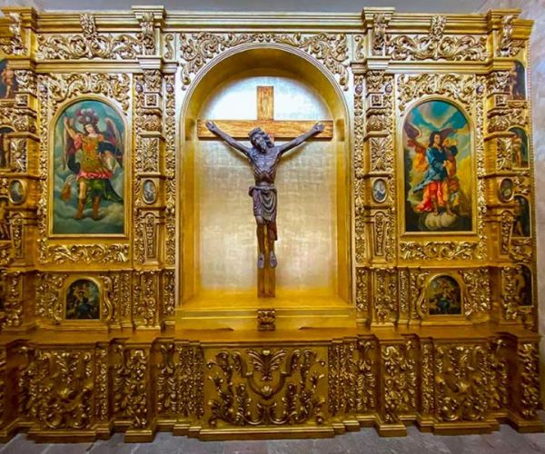 a gold wall with a statue of a crucifixion on it