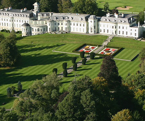 a large white building with a lawn and trees