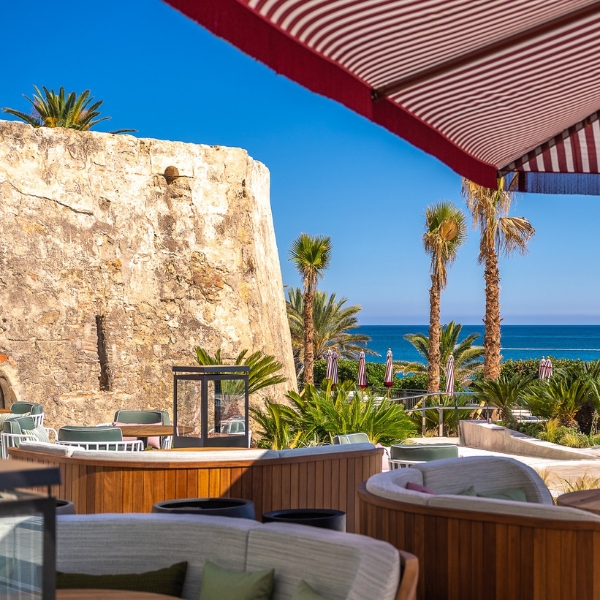 a beach bar with palm trees and a red and white striped awning