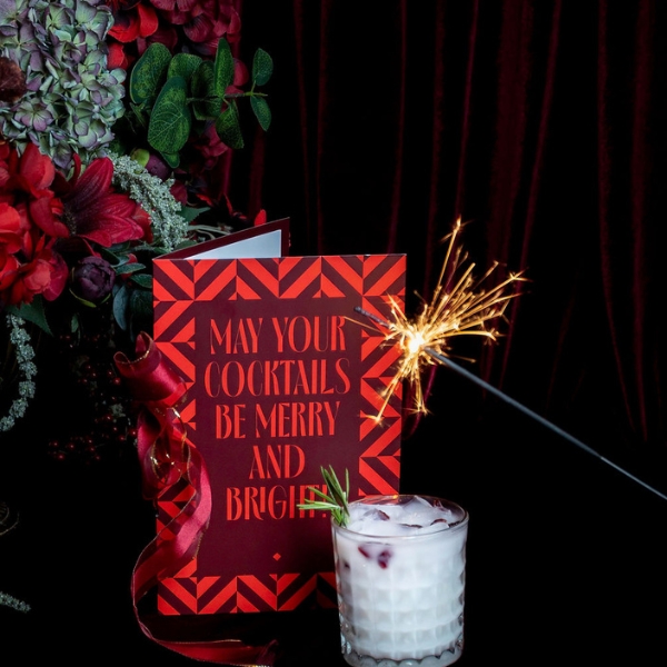 a card with a sparkler next to a glass of alcohol