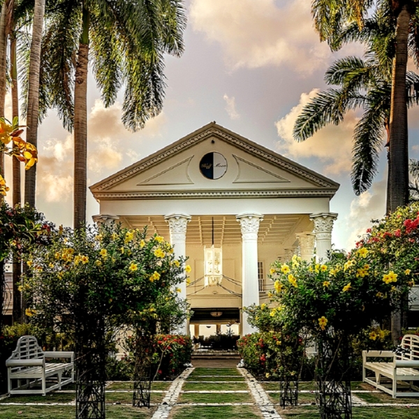 a building with columns and a clock in front of trees