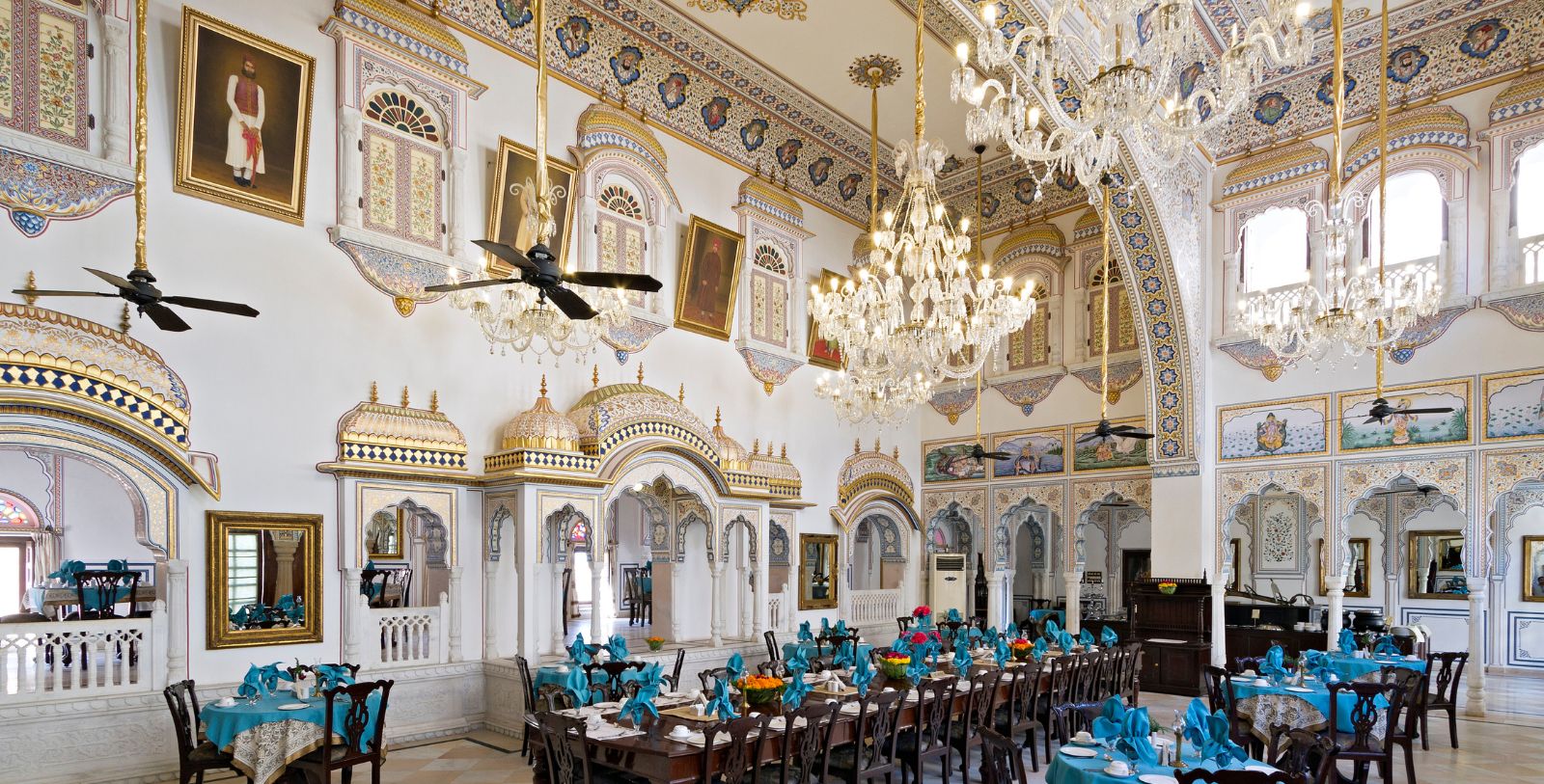 a large ornate room with tables and chandeliers