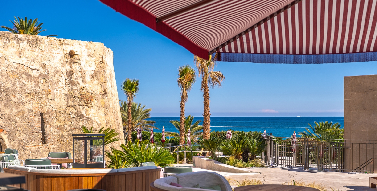a beach with palm trees and a red and white striped umbrella