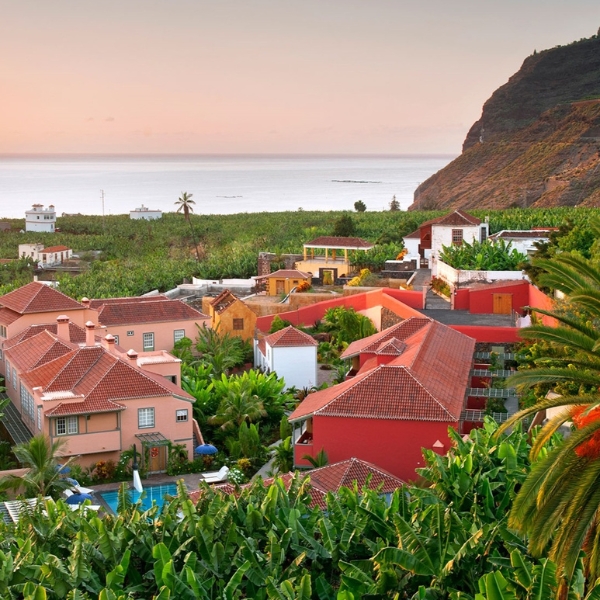 a group of houses with a pool in the middle of a tropical area
