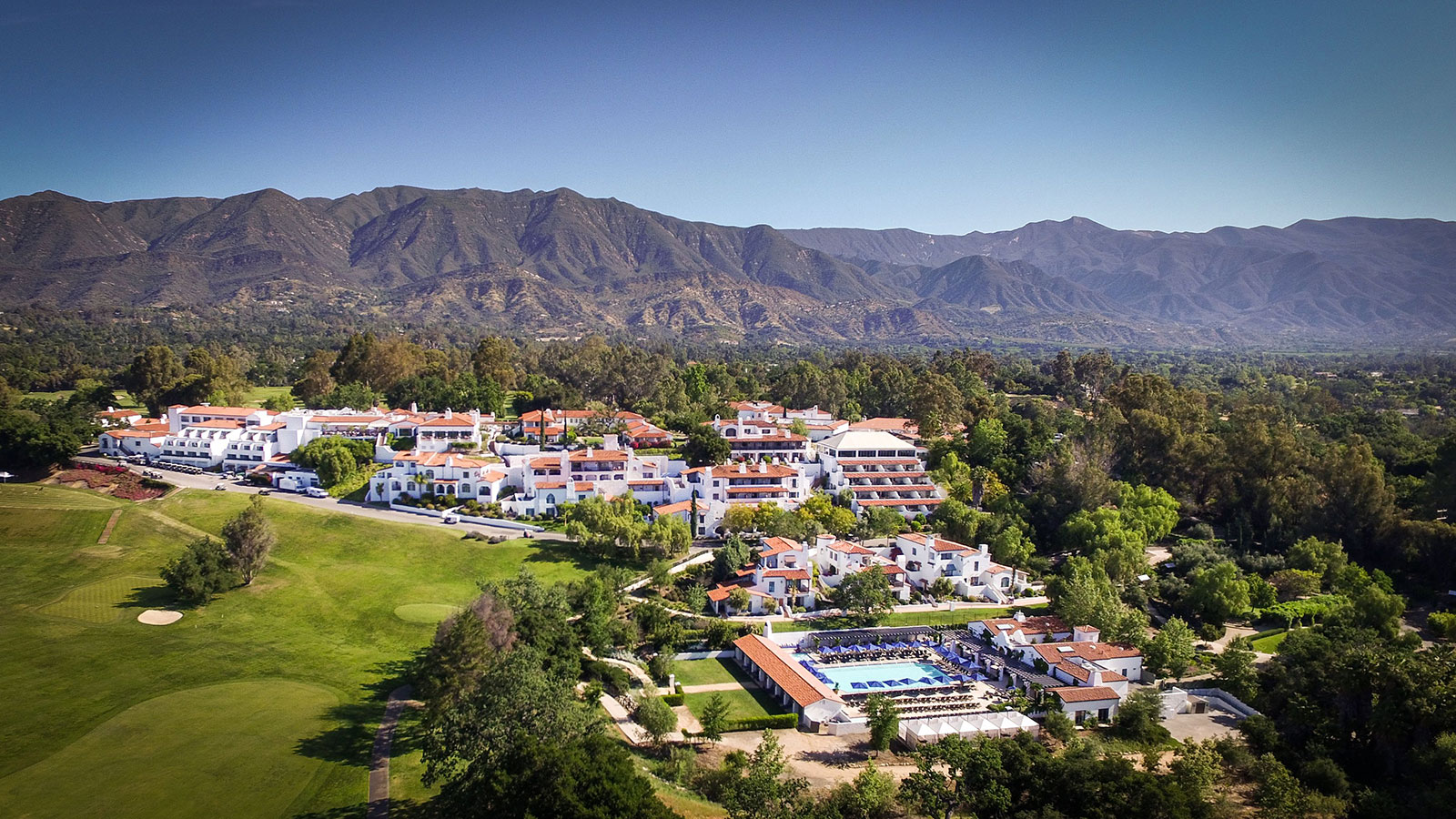 a large white building with a pool in front of a large mountain 7