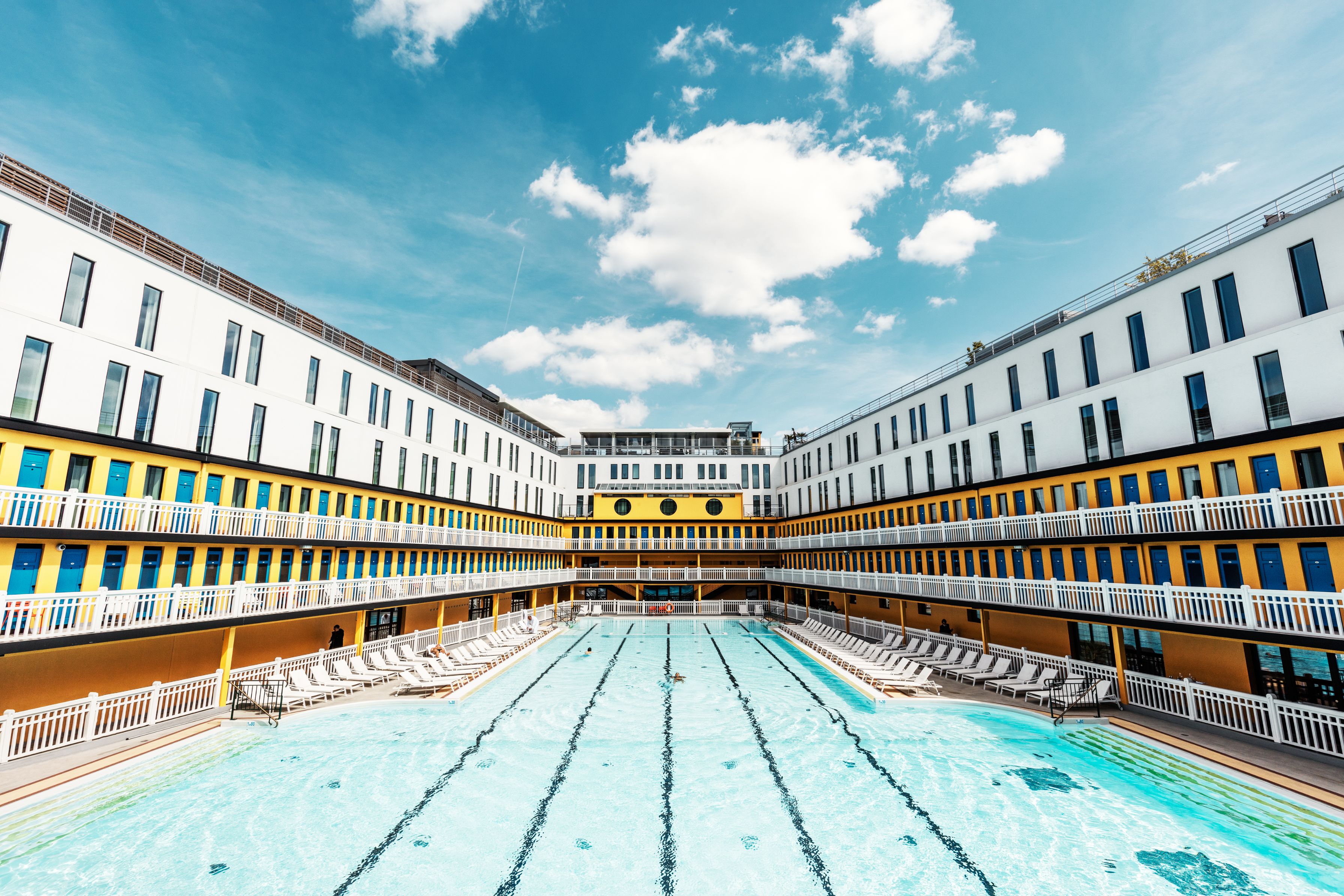 a swimming pool with chairs in front of a building