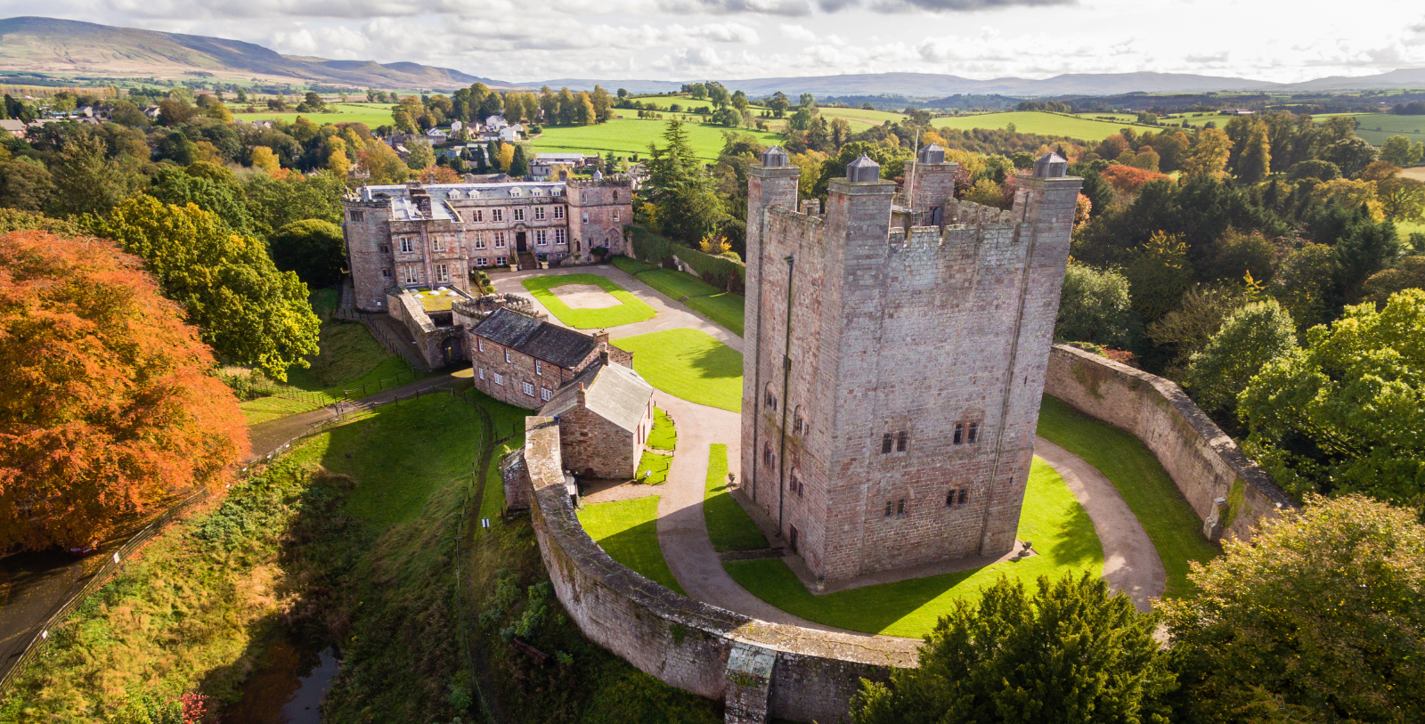 a castle with a stone wall and grass